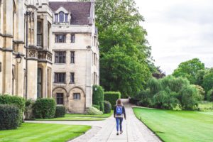 A student walking close to a building of the University of Oxford.