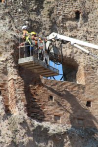 People working to preserve an ancient wall. 