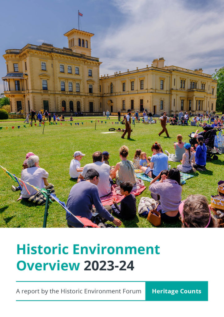 Included for decorative purposes, the cover of the report reads “Historic Environment Overview 2023-24. A report by the Historic Environment Forum – Heritage Counts”. Above the text is a photograph of a summer scene where people including family groups are sitting on grass enjoying entertainment displays in front of a large ochre-coloured historic building, set against blue skies with some light clouds.